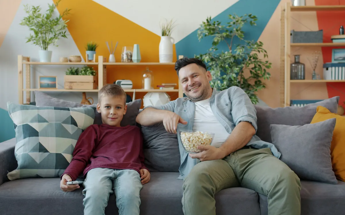 Father and son relaxing on the sofa watching IPTV on the living room TV