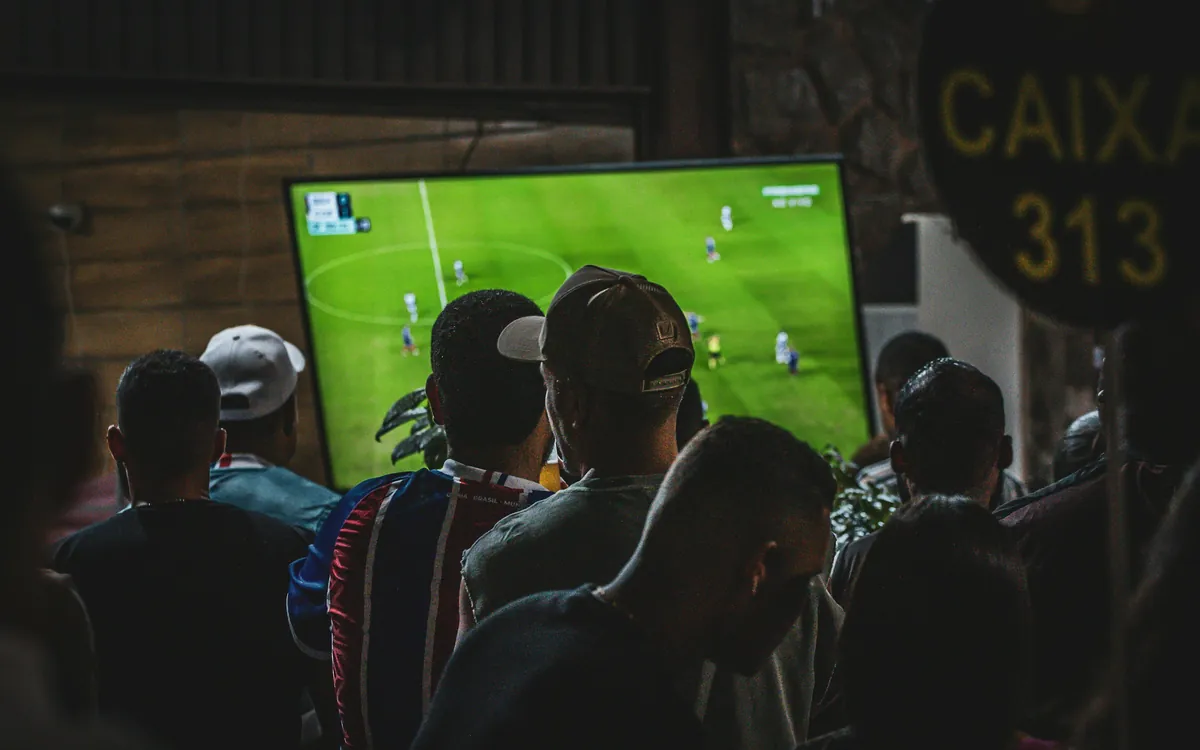 Group of friends watching a live football match on a big TV at home