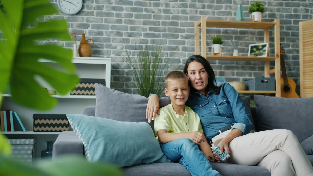 Mother and young son sitting together on a sofa watching television