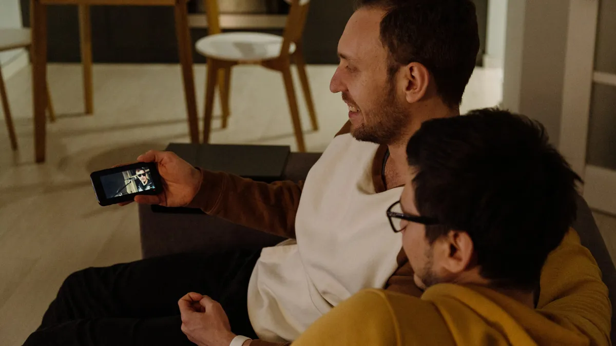 Two friends on a sofa watching a stream on an Android smartphone
