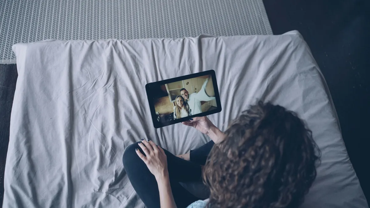 Woman lying on a bed watching a video on an iPad tablet